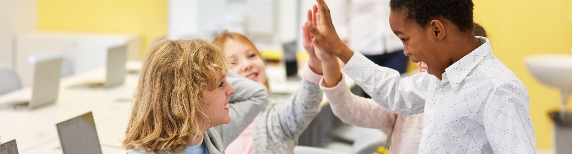 Kids display good positive behavior with a high five in classroom.