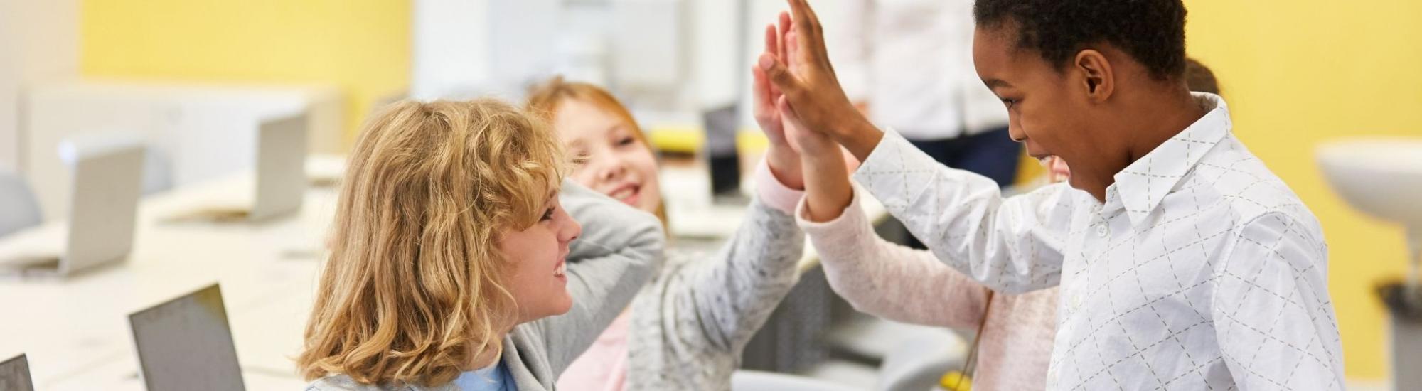 Kids display good positive behavior with a high five in classroom.