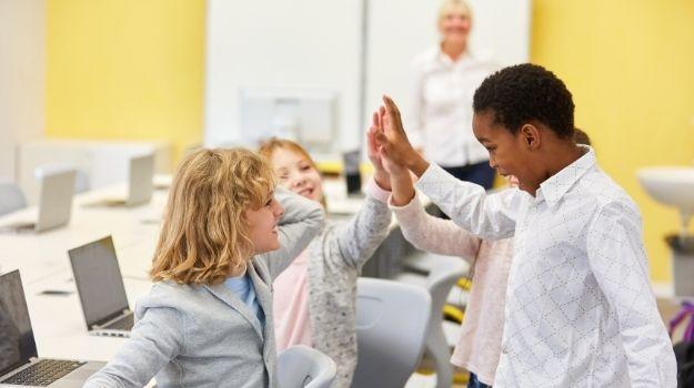 Kids display good positive behavior with a high five in classroom.
